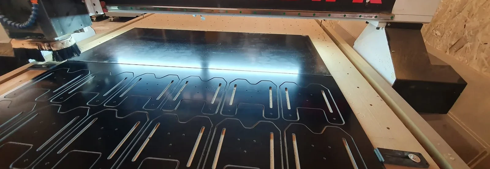 Fraiseuse CNC Gen3D en cours de découpe : pièces détourées dans un panneau, éclairage de la broche en fonctionnement